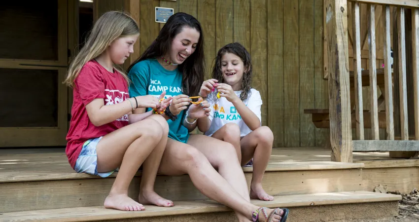 Two girls and a counselor sitting on the cabin steps