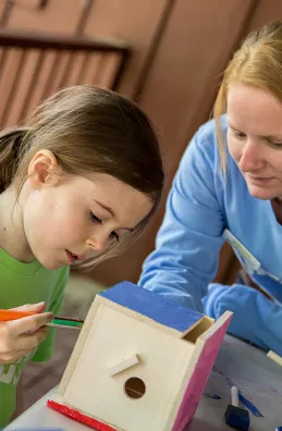 Mom and daughter painting a birdhouse