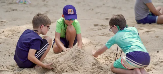 Three campers creating sandcastles at the Camp Kanata waterfront