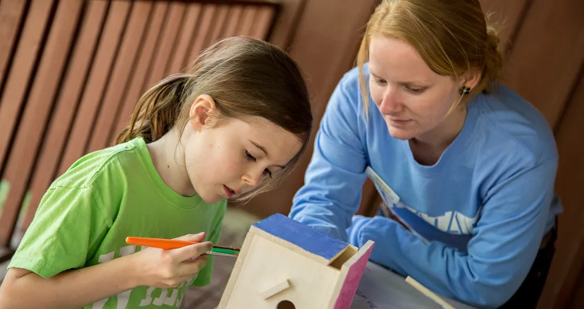 Mom and daughter painting a birdhouse